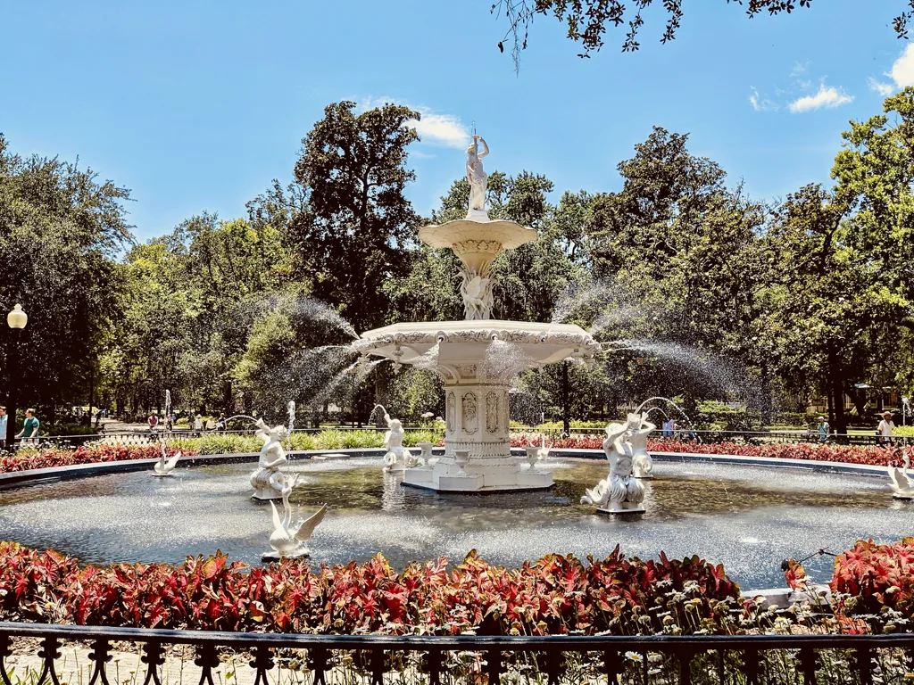 Forsyth Park fountain framed by red flowers and leafy trees in Savannah, Georgia