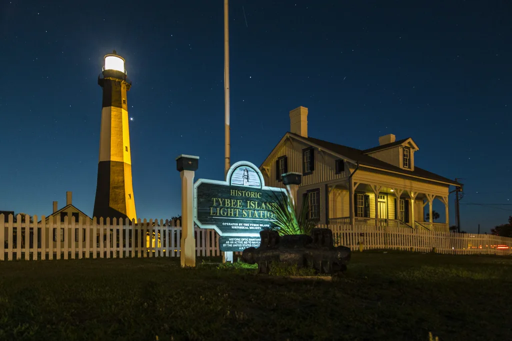 Tybee Island lighthouse rising above green grass beneath an evening sky