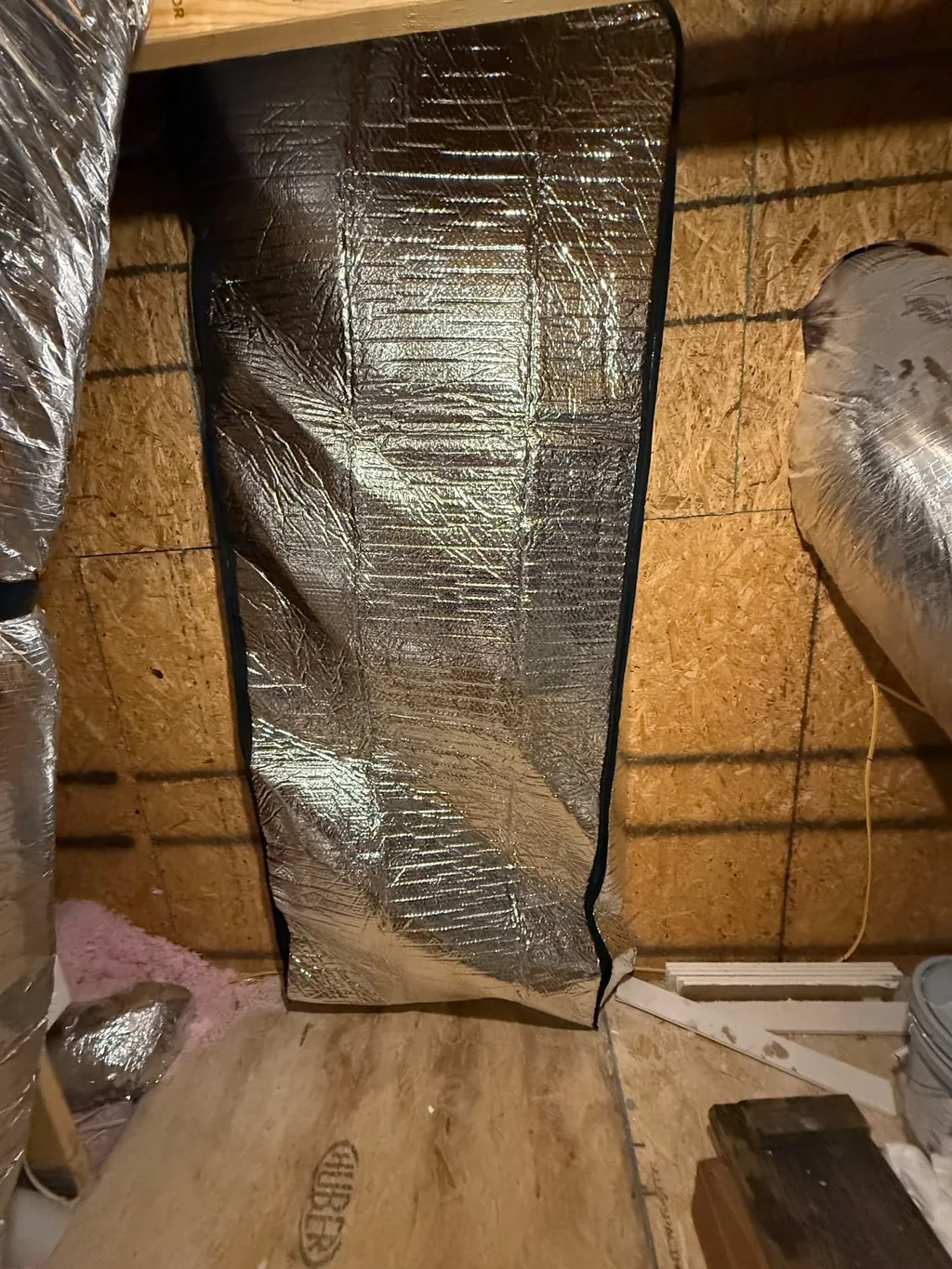 Reflective attic hatch cover installed upright beneath attic framing